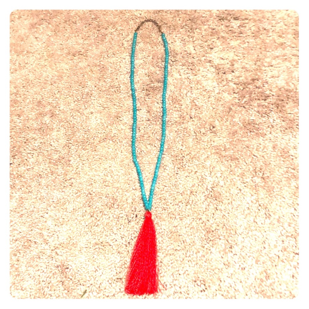 Long necklace with a red tassel at the end